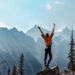 A person standing on a mountain with their arms raised, symbolizing quiet success, personal growth, resilience, and celebrating meaningful victories.