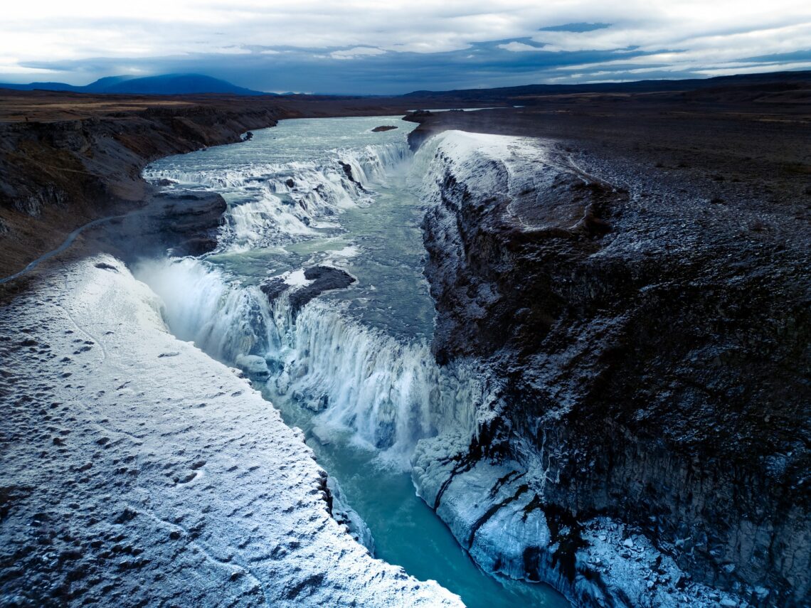 Snow-covered waterfall flowing through a dramatic rocky landscape