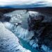Snow-covered waterfall flowing through a dramatic rocky landscape