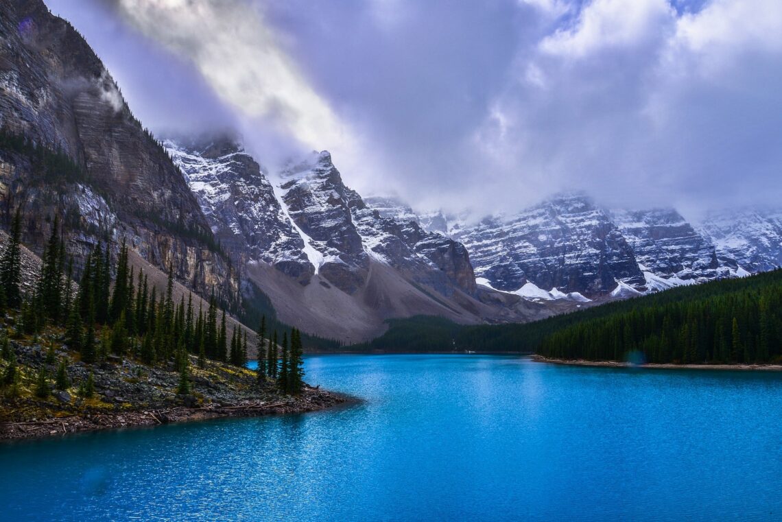 Turquoise mountain lake surrounded by evergreen trees and snow-covered mountains