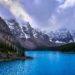 Turquoise mountain lake surrounded by evergreen trees and snow-covered mountains