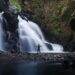 Person standing with open arms in front of a peaceful waterfall, symbolizing healing, self-discovery, and reconnecting with yourself.