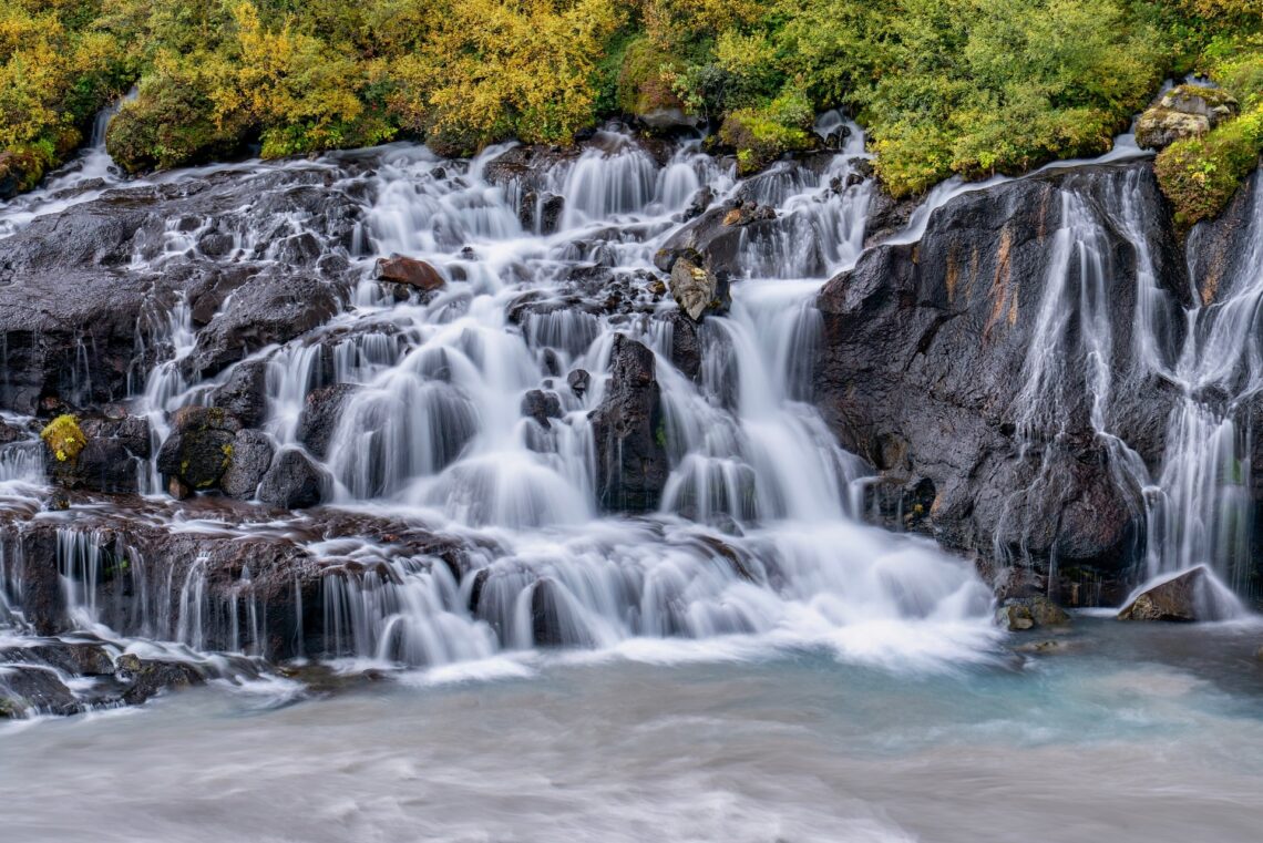Waterfall flowing over rocks surrounded by green foliage