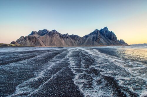 Mountain landscape with winding patterns across a dark shoreline