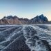 Mountain landscape with winding patterns across a dark shoreline